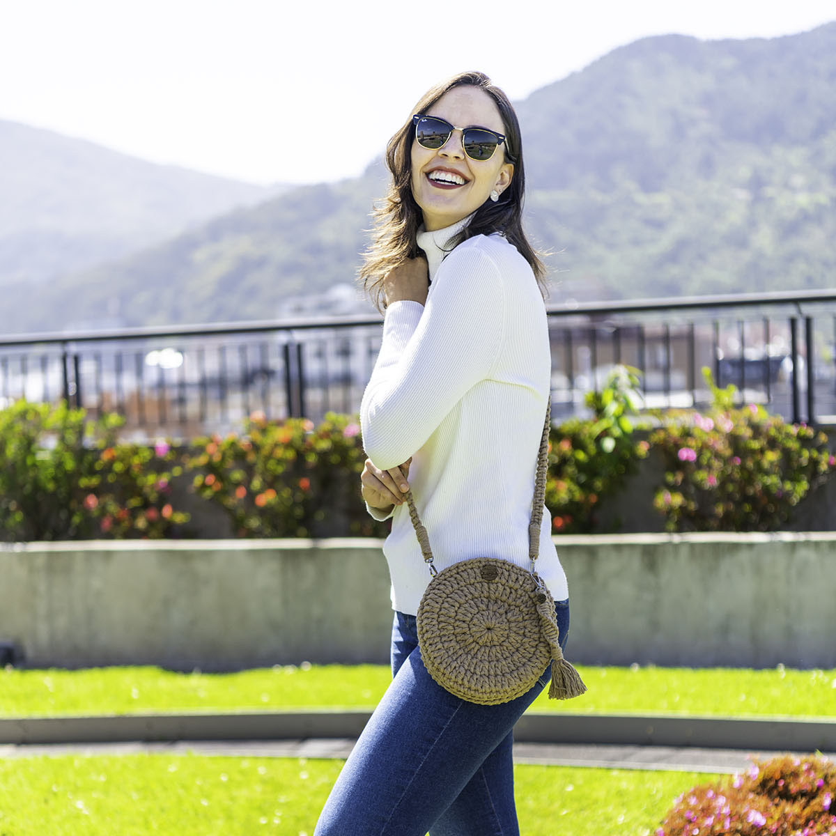 Bolsa redonda de macramê modelo Bella em tom terroso, detalhe da alça trançada.